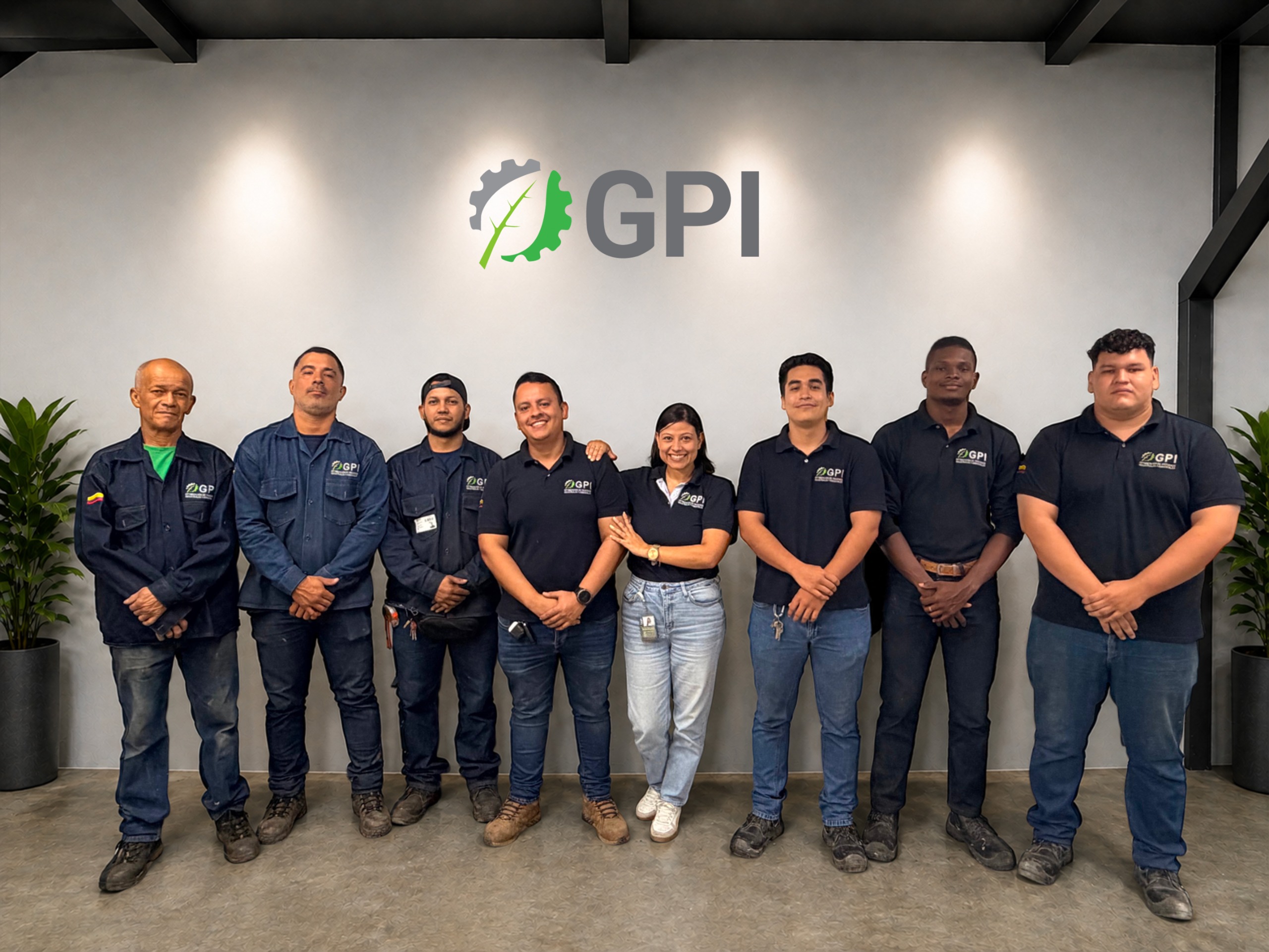 Equipo de GPI reunido en la sede de la empresa, frente a la pared con el logo corporativo